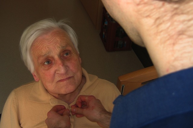Senior Being Dressed By Caregiver