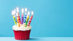 Cupcake with many lit candles in front of a blue background
